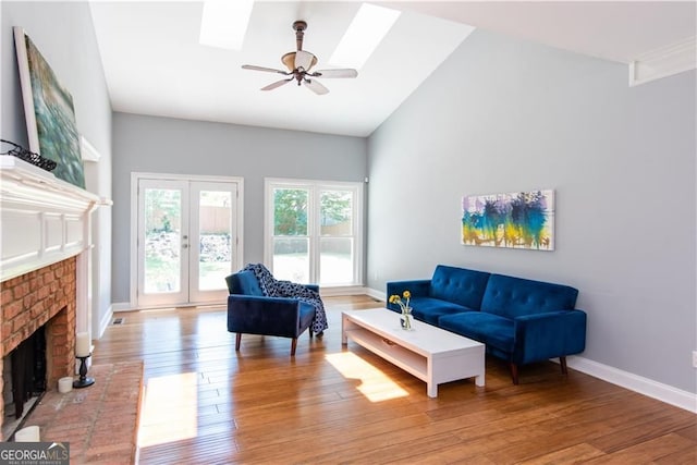 living room featuring french doors, ceiling fan, high vaulted ceiling, light hardwood / wood-style flooring, and a fireplace