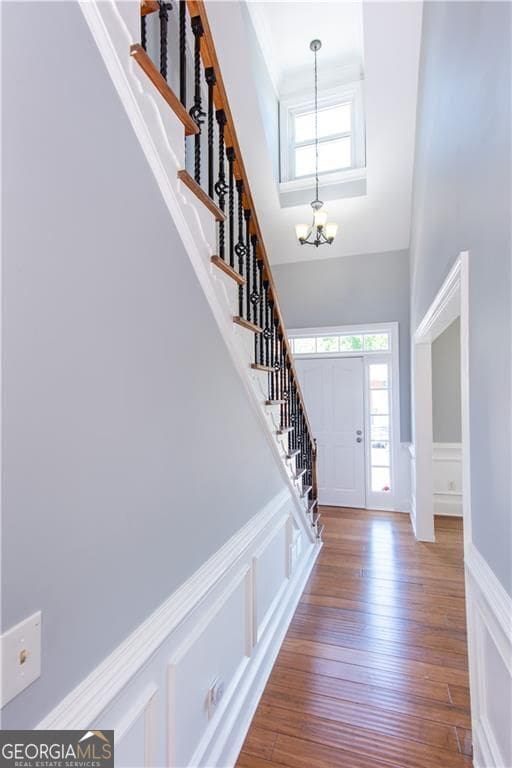 entrance foyer featuring a towering ceiling, hardwood / wood-style flooring, and an inviting chandelier