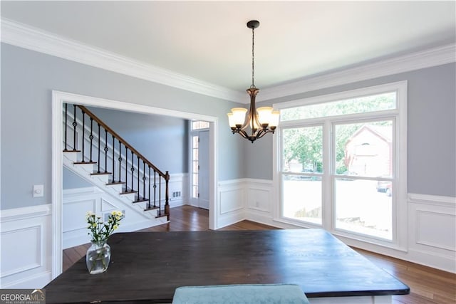 unfurnished dining area with dark wood-type flooring, crown molding, and a notable chandelier