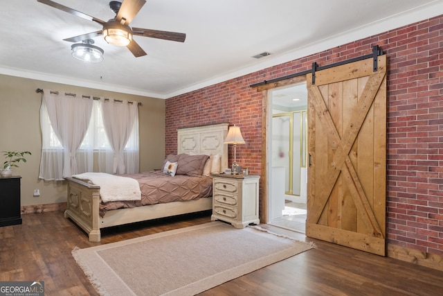 bedroom featuring a barn door, dark hardwood / wood-style floors, ceiling fan, and brick wall