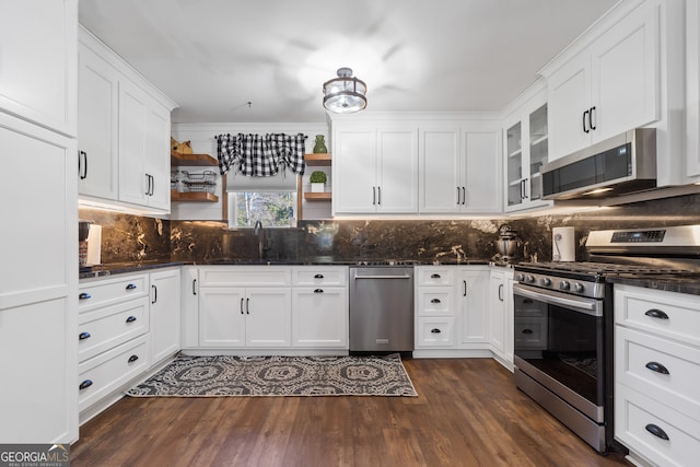 kitchen featuring dark hardwood / wood-style flooring, white cabinets, ornamental molding, and appliances with stainless steel finishes