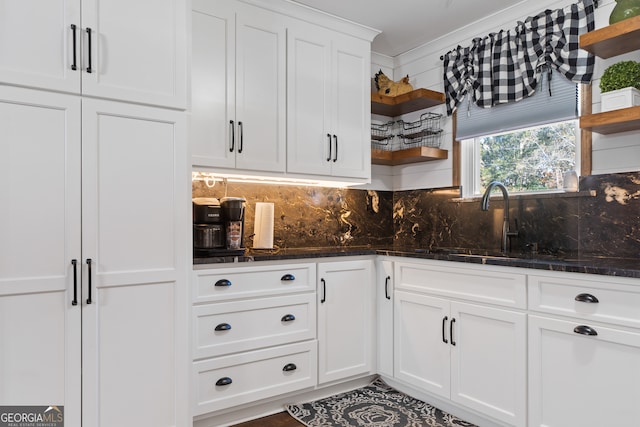 kitchen featuring dark stone counters, white cabinets, crown molding, sink, and decorative backsplash