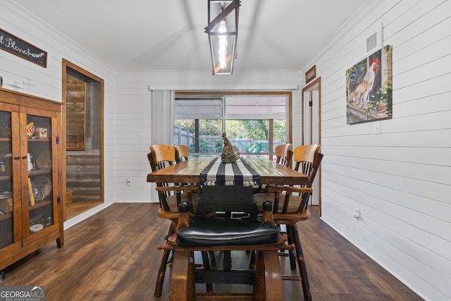 dining room featuring wooden walls, crown molding, and dark wood-type flooring