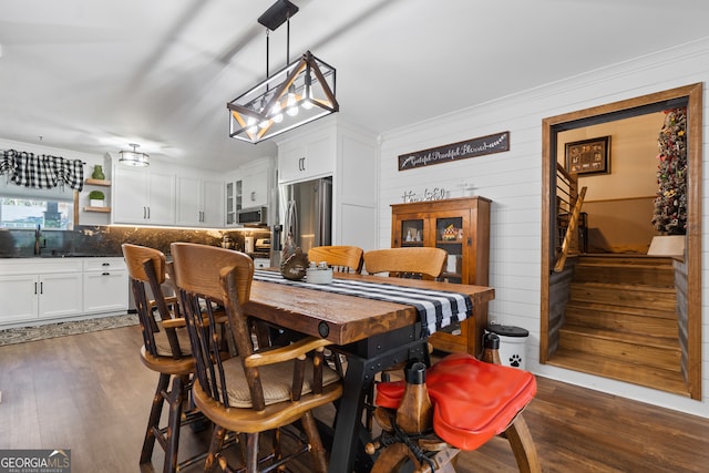 dining room featuring sink, ornamental molding, and dark wood-type flooring