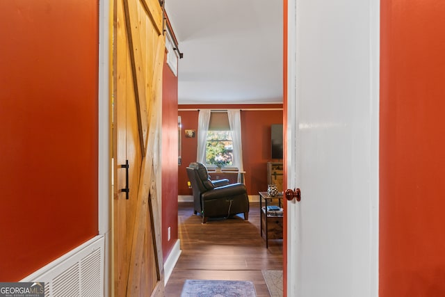 hall featuring a barn door, hardwood / wood-style flooring, and ornamental molding