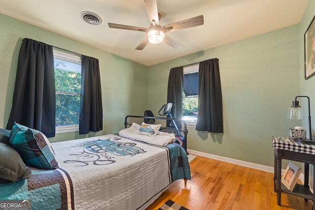 bedroom with ceiling fan, light hardwood / wood-style floors, and multiple windows