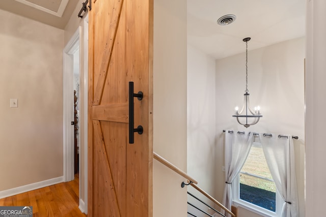 interior space with hardwood / wood-style floors, a barn door, and an inviting chandelier