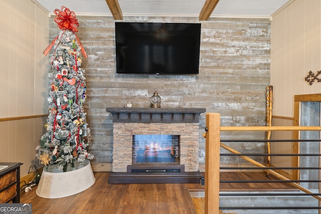 living room with a stone fireplace, wood walls, and hardwood / wood-style floors