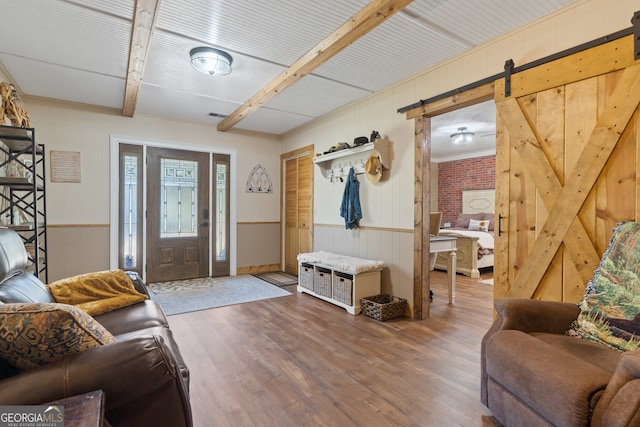 foyer with hardwood / wood-style flooring, a barn door, beam ceiling, and wooden walls