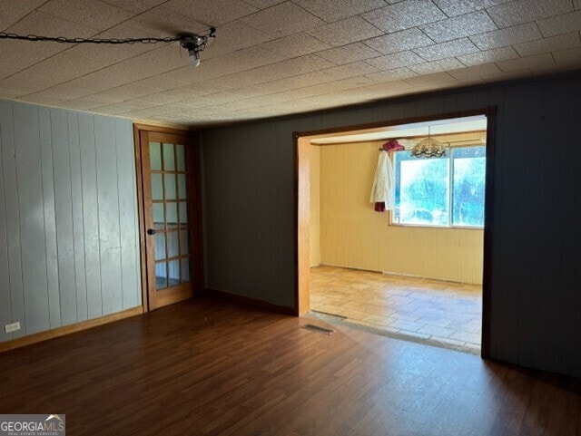 spare room with hardwood / wood-style floors, a notable chandelier, and wood walls