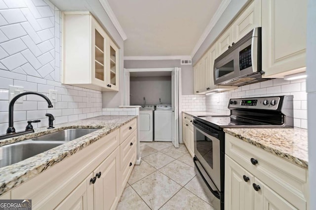 kitchen with sink, stainless steel appliances, crown molding, washer and clothes dryer, and light tile patterned flooring