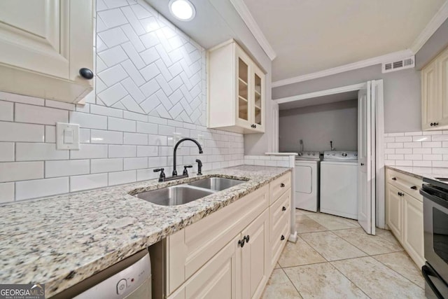 kitchen with light stone countertops, washer and clothes dryer, ornamental molding, and sink