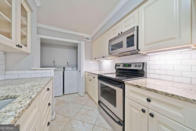 kitchen featuring light stone countertops, ornamental molding, stainless steel appliances, light tile patterned floors, and separate washer and dryer