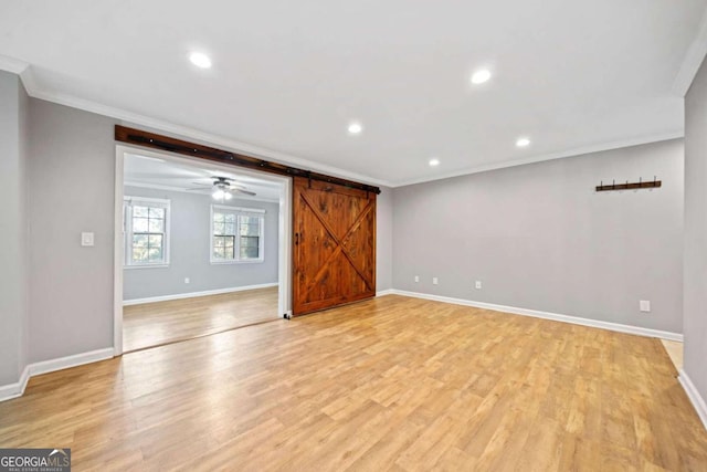 unfurnished living room featuring a barn door, light hardwood / wood-style flooring, and crown molding