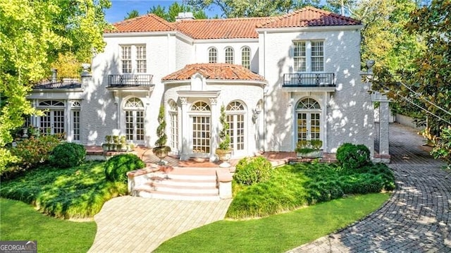 mediterranean / spanish house featuring a balcony and french doors