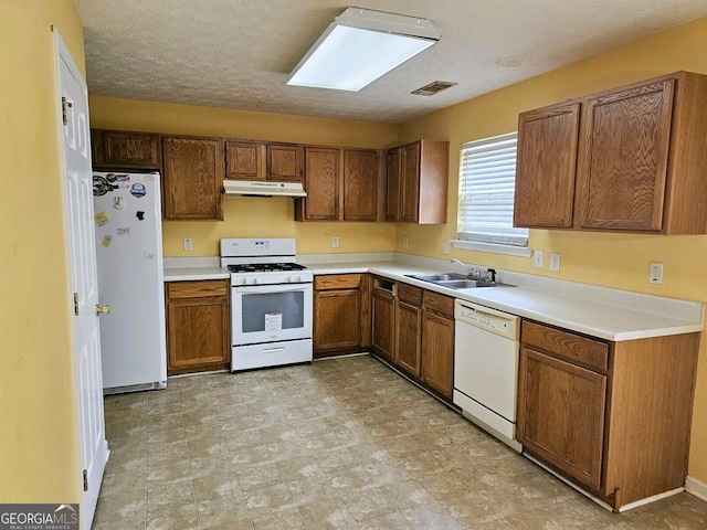 kitchen featuring a textured ceiling, sink, and white appliances