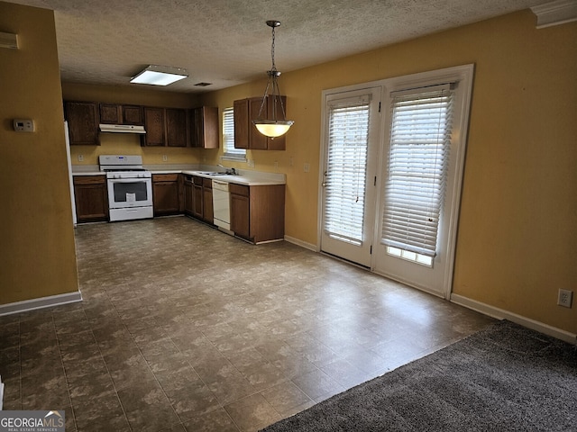 kitchen featuring a textured ceiling, sink, hanging light fixtures, and white appliances