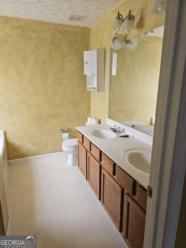 bathroom with vanity, a textured ceiling, and toilet