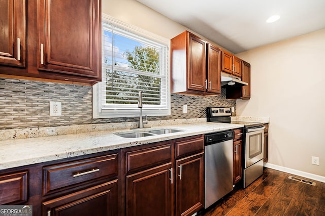 kitchen with light stone countertops, tasteful backsplash, stainless steel appliances, dark wood-type flooring, and sink