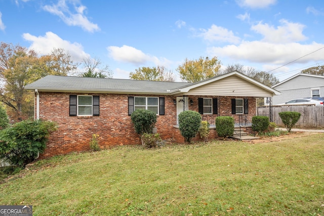 ranch-style house featuring covered porch and a front yard