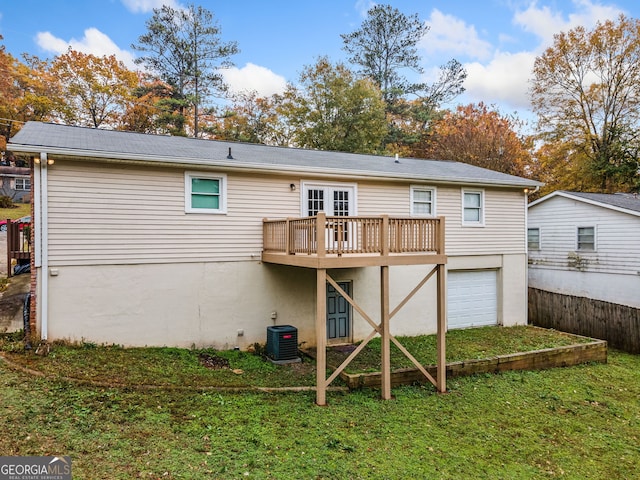 rear view of property featuring central AC, a yard, a deck, and a garage