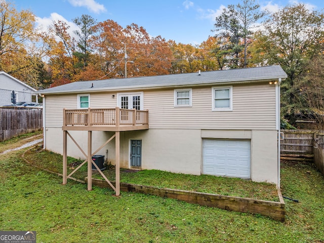 back of property featuring a lawn, a garage, a wooden deck, and central AC