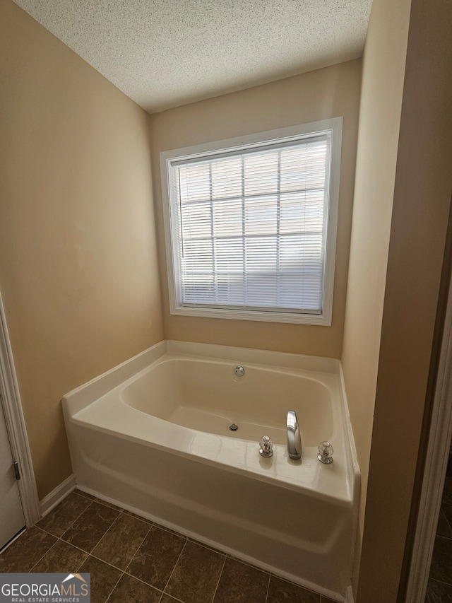 bathroom featuring a bath, a textured ceiling, and tile patterned floors