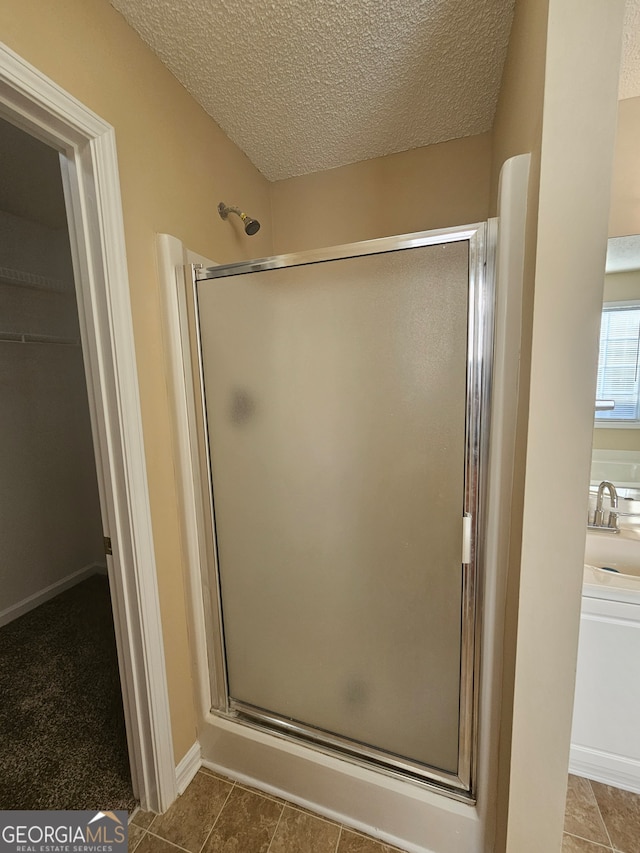 bathroom featuring a textured ceiling, tile patterned floors, and walk in shower