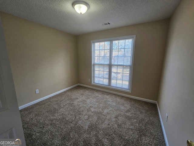 spare room featuring dark carpet and a textured ceiling