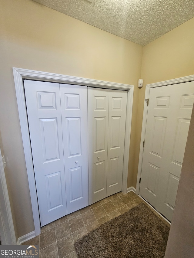 doorway with dark tile patterned flooring and a textured ceiling