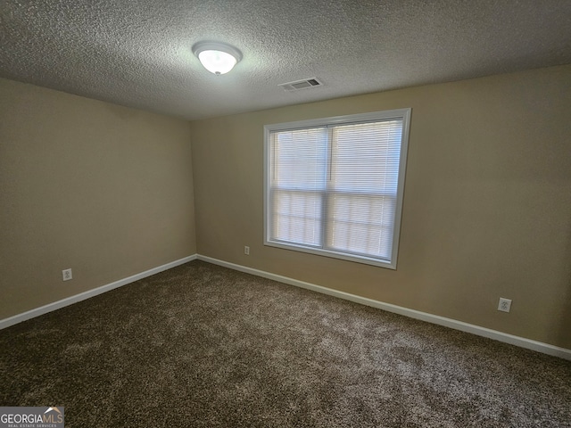 spare room featuring dark colored carpet and a textured ceiling