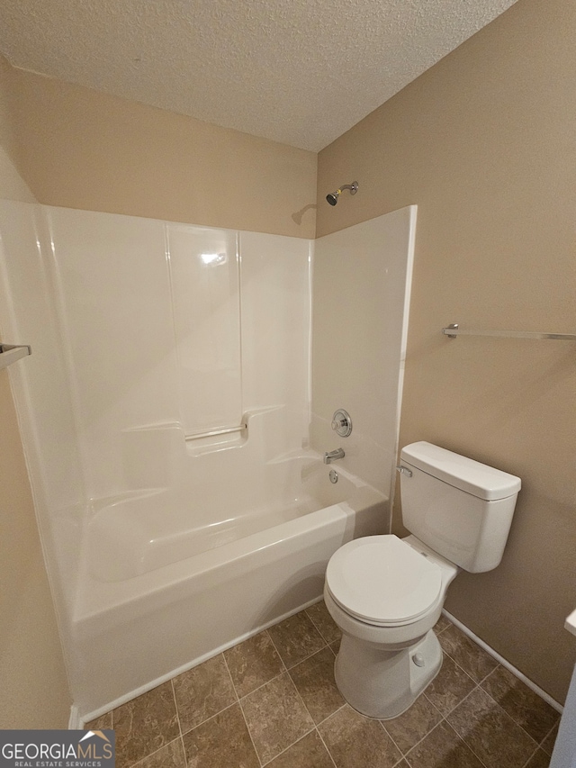 bathroom featuring tile patterned floors, shower / washtub combination, a textured ceiling, and toilet