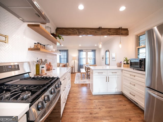 kitchen with kitchen peninsula, appliances with stainless steel finishes, pendant lighting, wood-type flooring, and white cabinetry