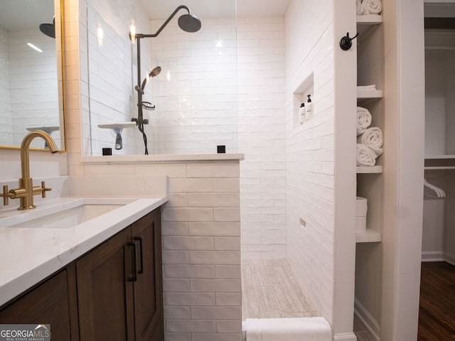 bathroom with built in shelves, vanity, wood-type flooring, and tiled shower