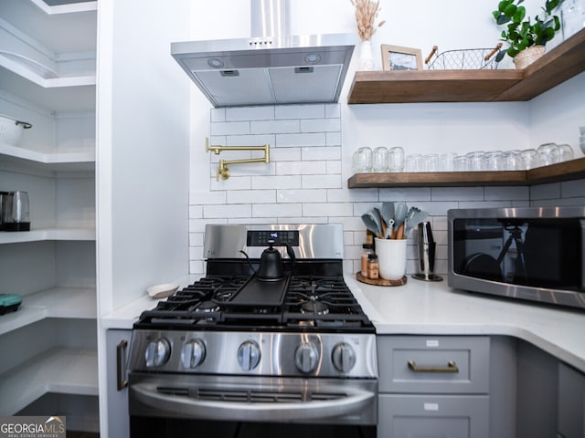 kitchen with backsplash, gray cabinetry, stainless steel appliances, and range hood