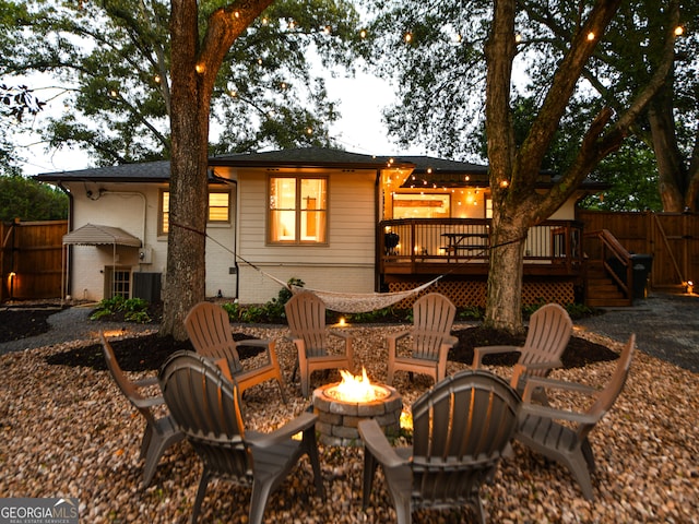 back of property with a deck and an outdoor fire pit