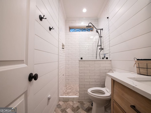 bathroom featuring vanity, toilet, and tiled shower