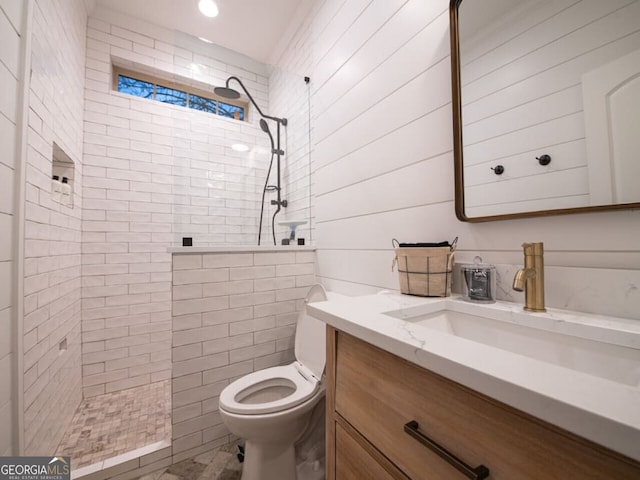 bathroom featuring a tile shower, vanity, and toilet