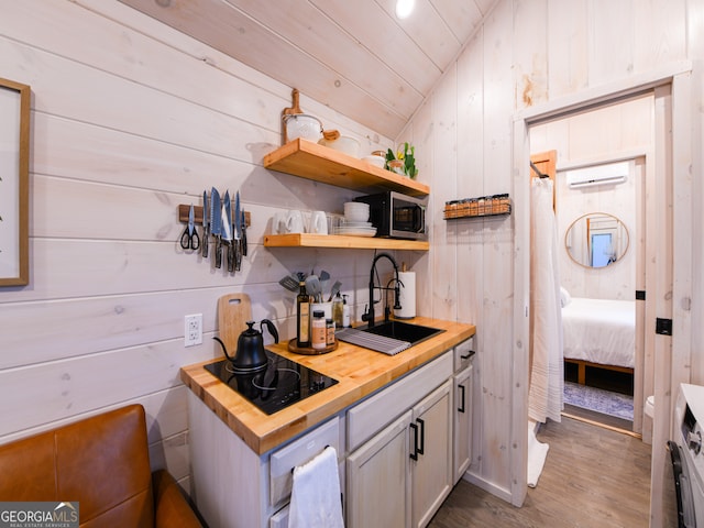 kitchen featuring wooden walls, sink, butcher block counters, dark hardwood / wood-style floors, and lofted ceiling