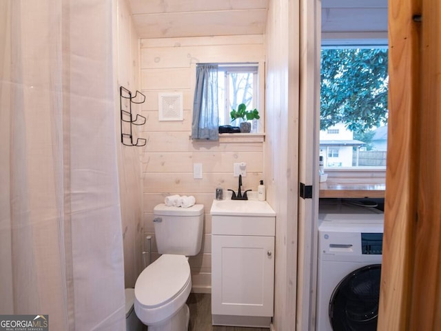 bathroom featuring washer / clothes dryer, toilet, a wealth of natural light, and wood walls