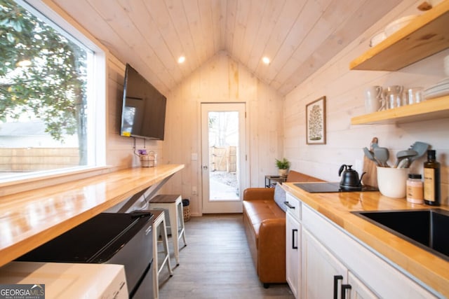 kitchen featuring wooden counters, white cabinets, plenty of natural light, and lofted ceiling