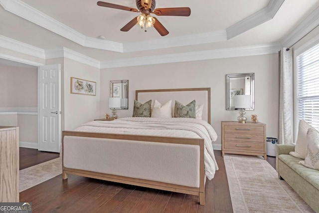 bedroom with hardwood / wood-style flooring, ceiling fan, and a tray ceiling