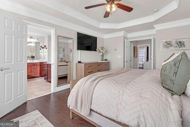 bedroom featuring connected bathroom, ceiling fan, dark hardwood / wood-style flooring, a tray ceiling, and ornamental molding