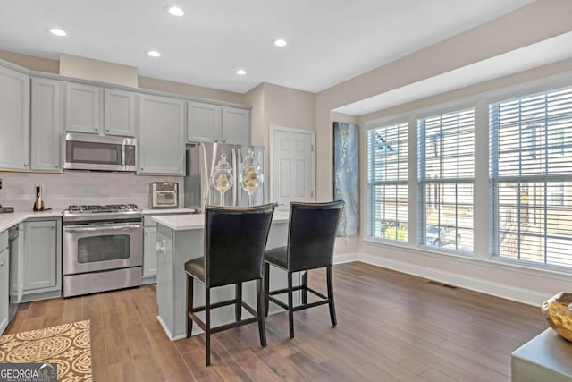 kitchen featuring backsplash, appliances with stainless steel finishes, a breakfast bar area, a kitchen island, and light wood-type flooring