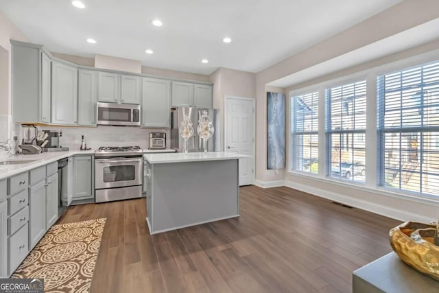 kitchen featuring decorative backsplash, gray cabinetry, stainless steel appliances, dark hardwood / wood-style floors, and a kitchen island