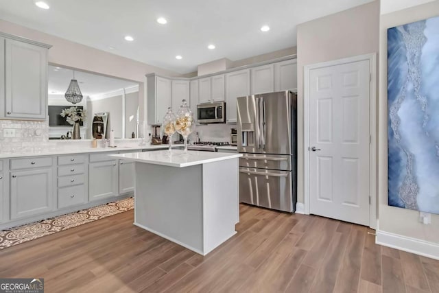 kitchen featuring backsplash, gray cabinetry, stainless steel appliances, a center island with sink, and light hardwood / wood-style floors