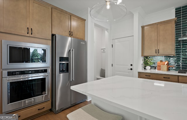 kitchen with light stone countertops, light hardwood / wood-style floors, a breakfast bar area, decorative backsplash, and appliances with stainless steel finishes