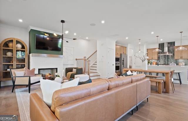 living room featuring crown molding, light hardwood / wood-style floors, and a brick fireplace