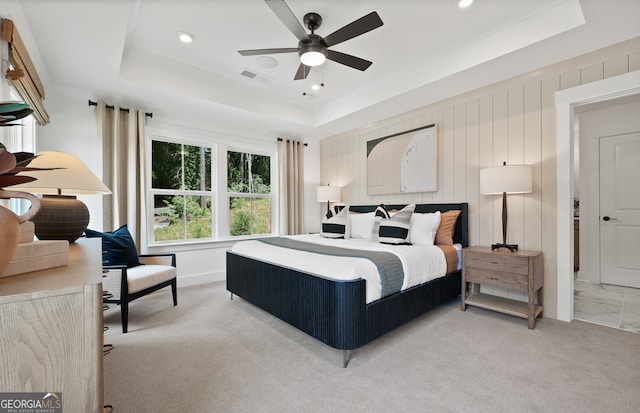 bedroom featuring ceiling fan, light carpet, and a tray ceiling