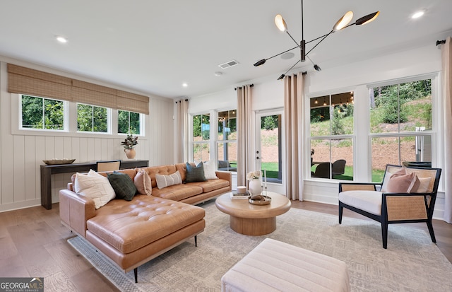 living room featuring plenty of natural light, light hardwood / wood-style floors, and a chandelier